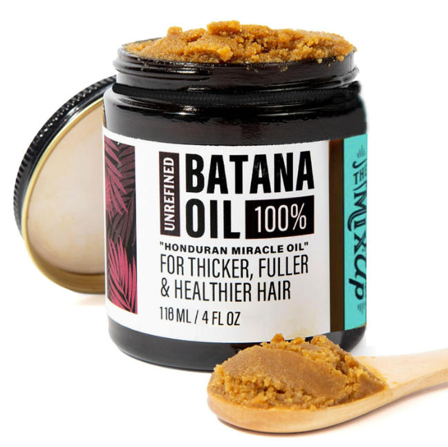 A jar of unrefined golden-brown batana oil in a dark glass container with white and teal label for glow restore hair mask