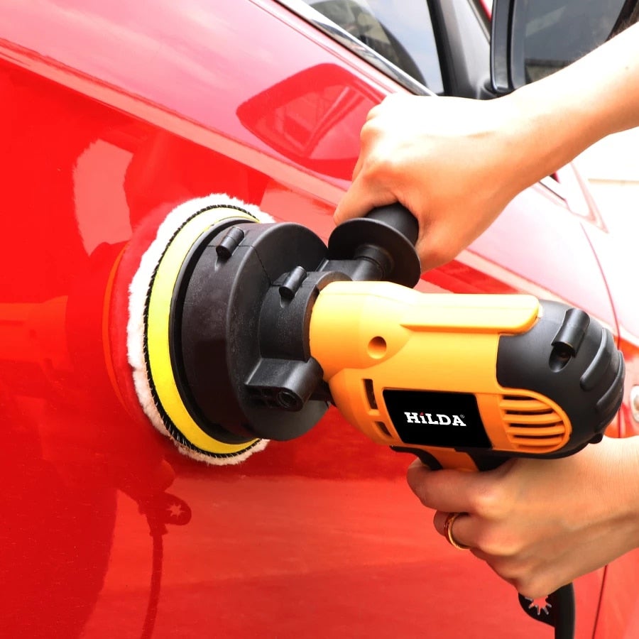 Yellow and black Hilda electric car polisher tool with a white yellow and black buffing pad in use