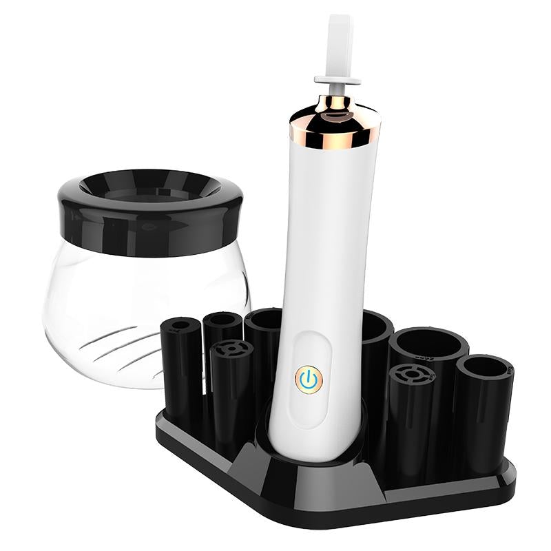 White electric makeup brush cleaner and dryer with rose gold accents in black charging stand and interchangeable brushes
