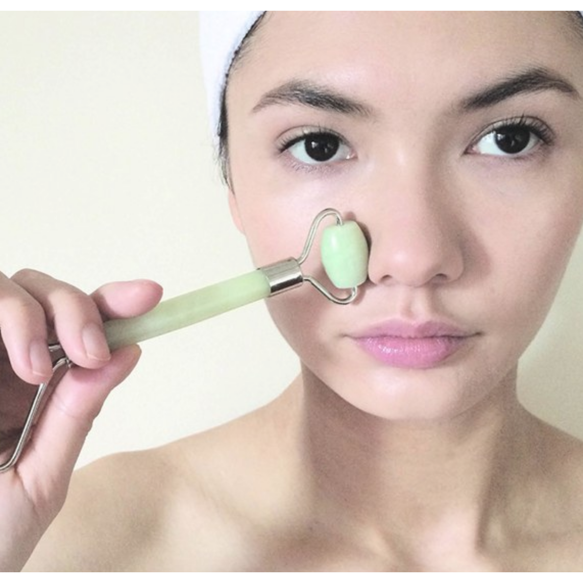 Double head jade face roller with pale green jade stones and metallic handle for facial massage and skincare