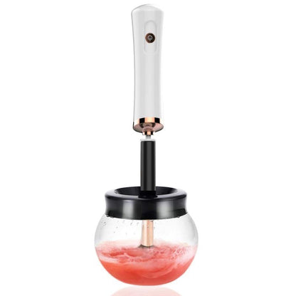 Electric makeup brush cleaner and dryer with white and rose gold head and black handle in a jar of pink liquid